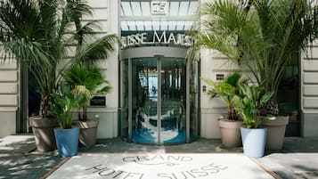 The entrance to Grand Hotel Suisse with a revolving door and potted plants.