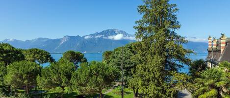 A parking area with cars, a view of mountains, and a body of water.