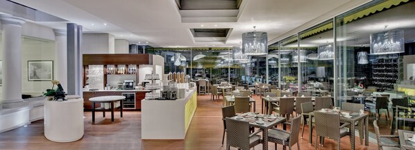 Un interior de restaurante moderno con una zona de bar central, mesas y sillas para comer.