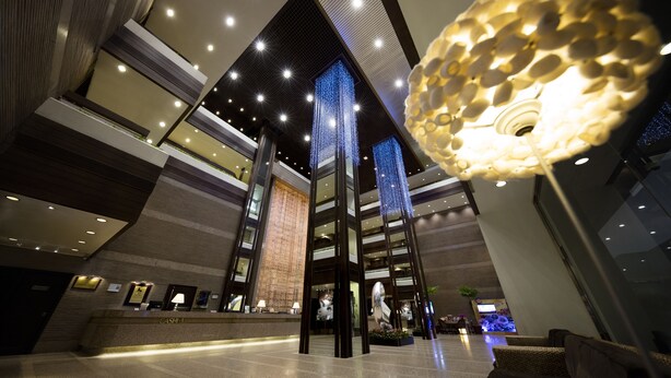 A modern lobby with a reception desk, high ceilings, and a decorative light fixture. - Regal Riverside Hotel (Sha Tin)