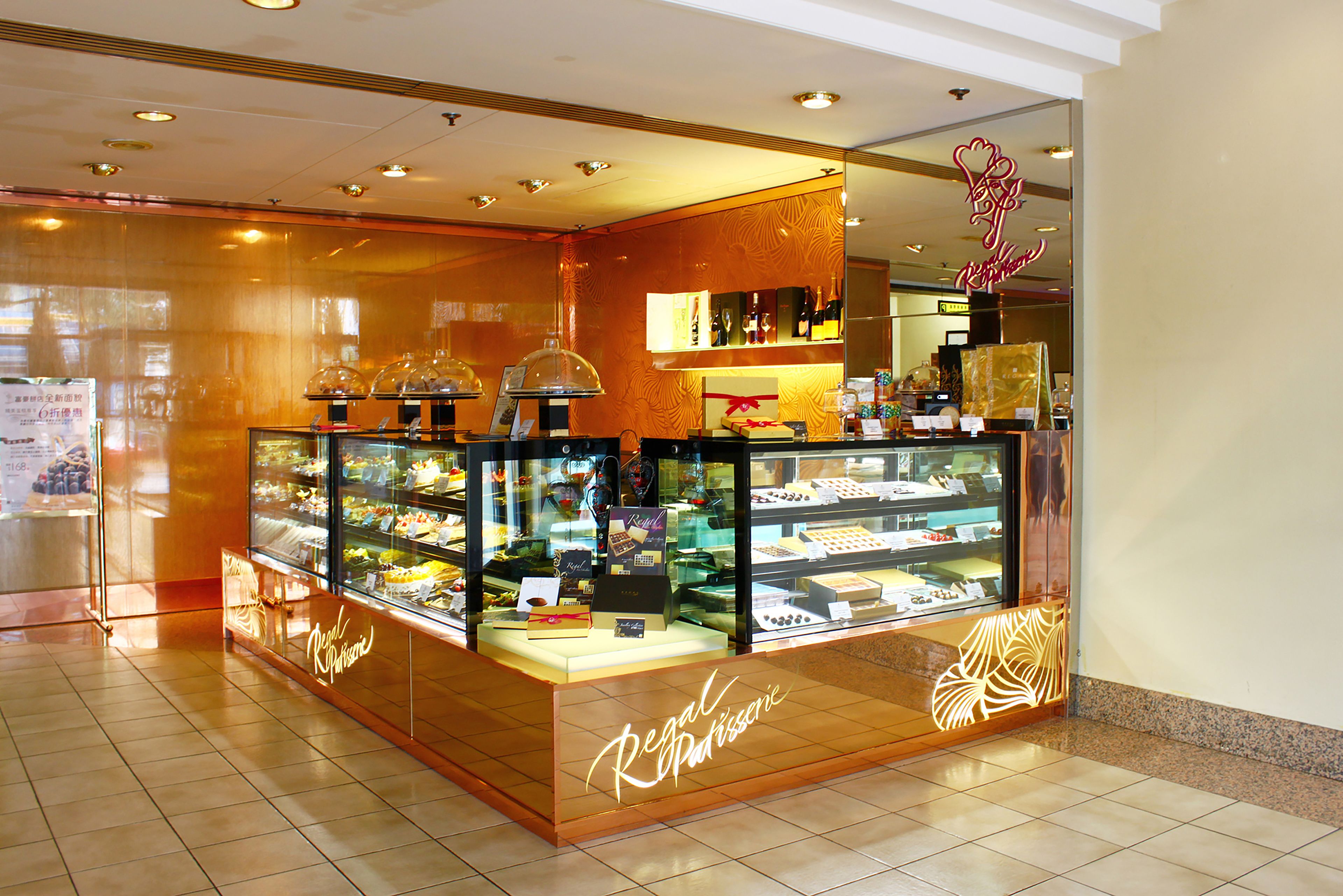 A bakery display with a glass case showcasing pastries and cakes, and a neon sign above the entrance.