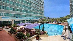 A hotel pool area with multiple levels of balconies, outdoor seating, and a clear view of the pool. - Regal Riverside Hotel (Sha Tin)