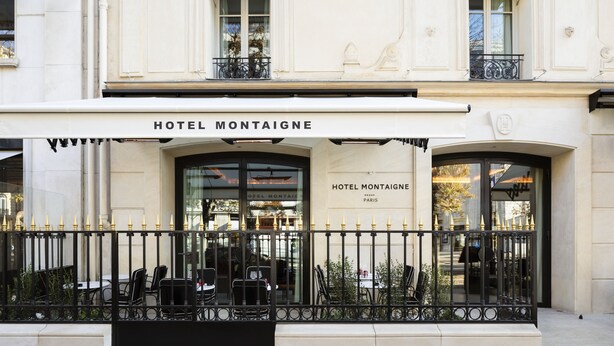 Um edifício com uma placa indicando "HOTEL MONTAIGNE" e "HOTEL MONTAIGNE PARIS".