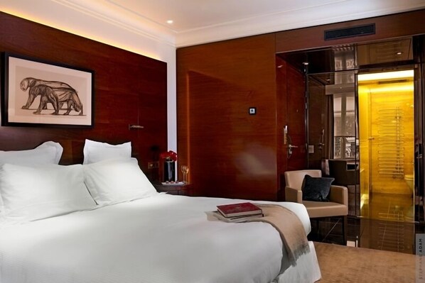 Habitación de hotel con una cama grande, una silla, un escritorio y una puerta que da a un baño.