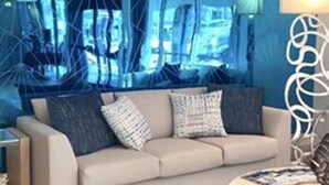 A living room with a blue accent wall, a sofa, a coffee table, and a patterned rug. - Comfort Inn Oceanside Deerfield Beach (Deerfield Beach)