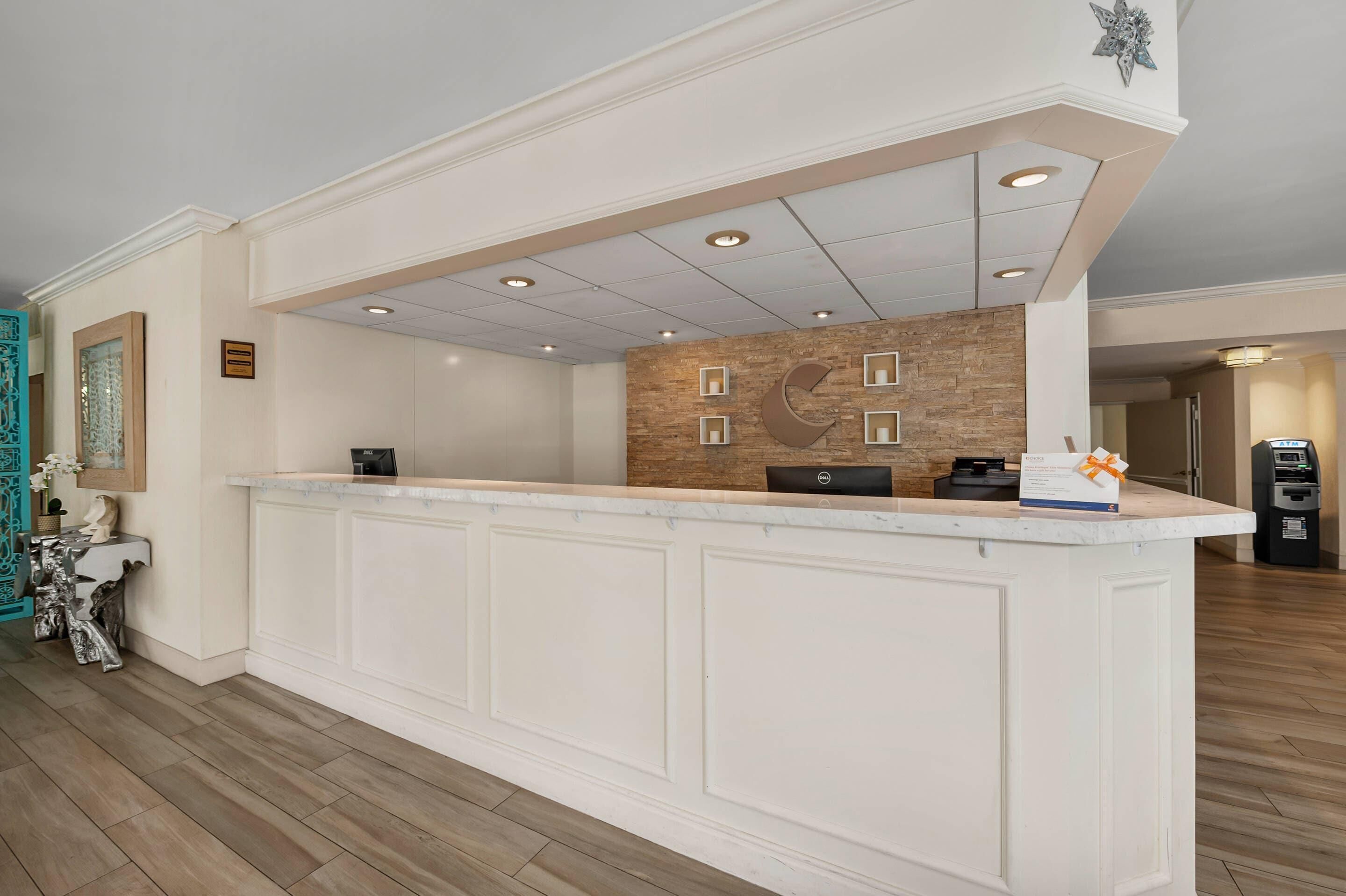 A reception area with a marble counter, a wall-mounted clock, and a decorative wall piece.