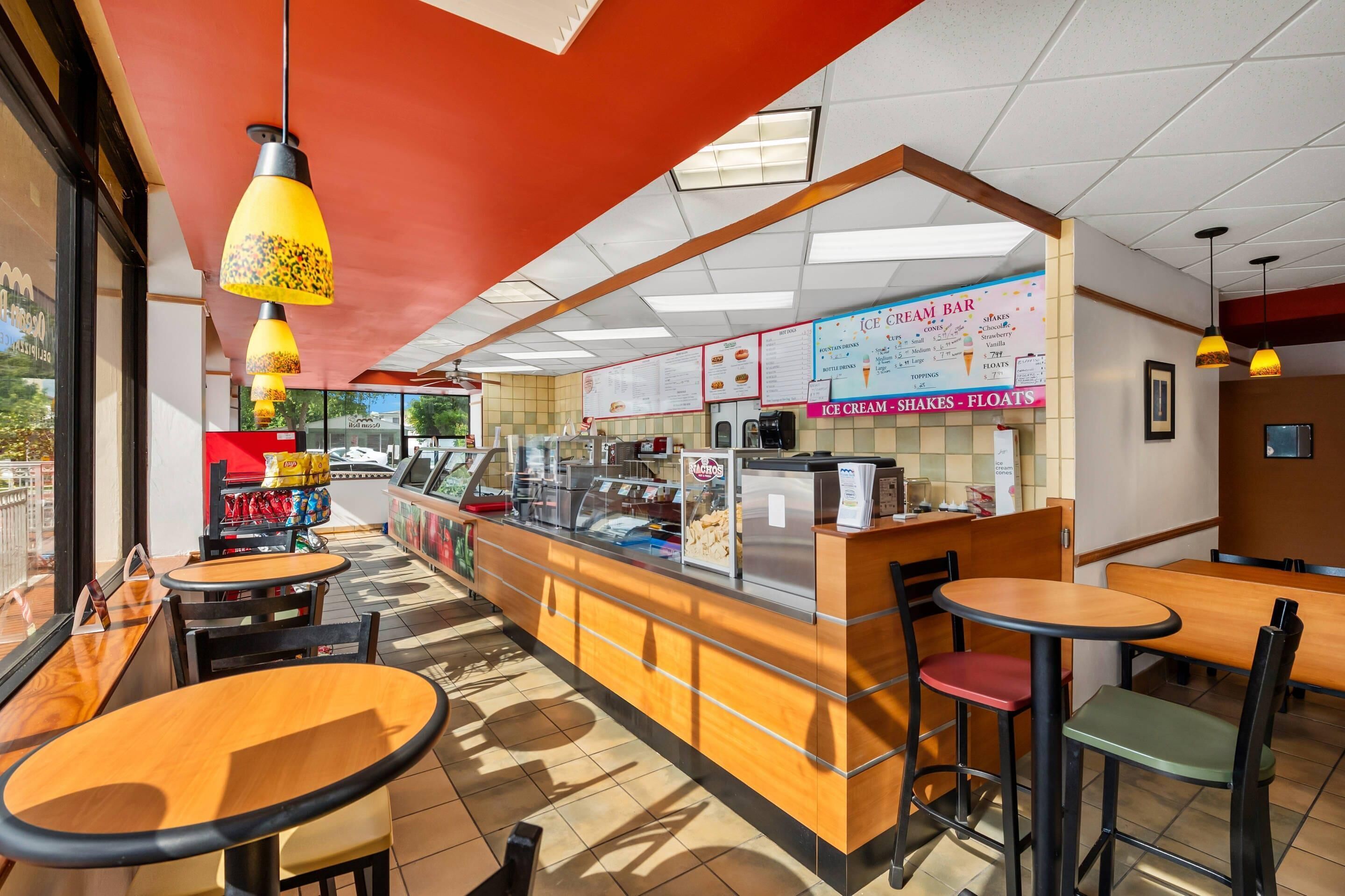 Un interior de restaurante con mostrador, pizarras de menú y distribución de mesas.