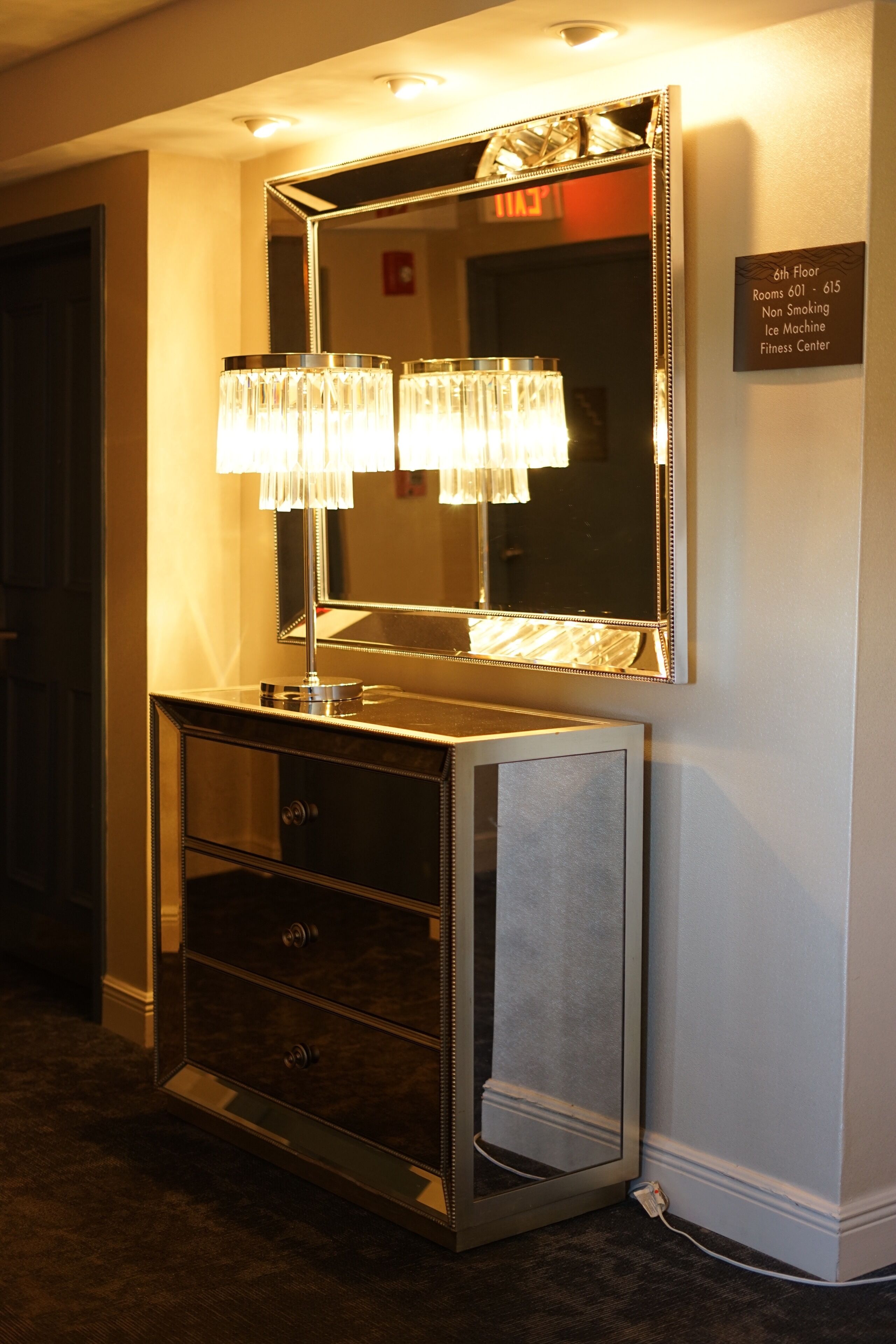 A hotel bathroom vanity with a large mirror, a sink, and a vanity with drawers. There is a sign indicating the 6th floor and non-smoking rooms.