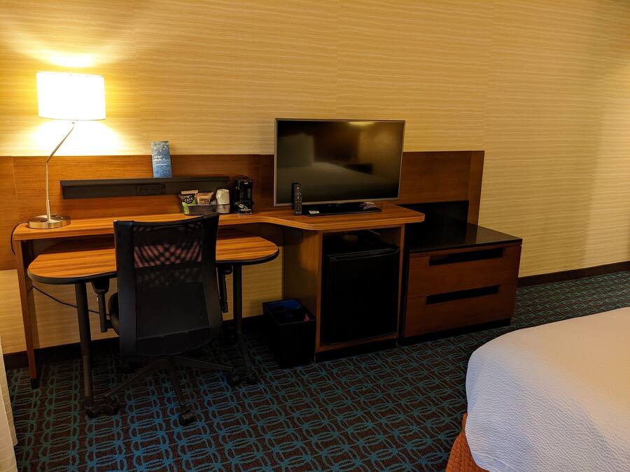 Una habitación de hotel con escritorio, silla, televisor y cama.