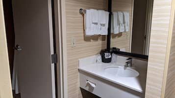 Een badkamer met een witte wastafel, een spiegel en een handdoekrek met meerdere handdoeken.