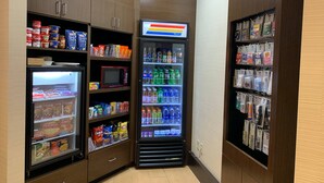 A corner of a hotel room with a refrigerator stocked with snacks and beverages, a microwave, and shelves with toiletries and other items. - Fairfield Inn By Marriott Concord (Concord)