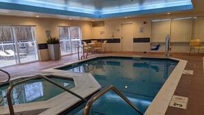 An indoor swimming pool with clear water, a diving board, and a sunlit patio area with outdoor seating. - Fairfield Inn By Marriott Concord (Concord)