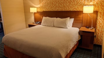 A hotel room with a large bed, two bedside tables, a telephone, and two lamps.