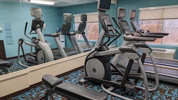 A gym with treadmills, an elliptical, and a bench.