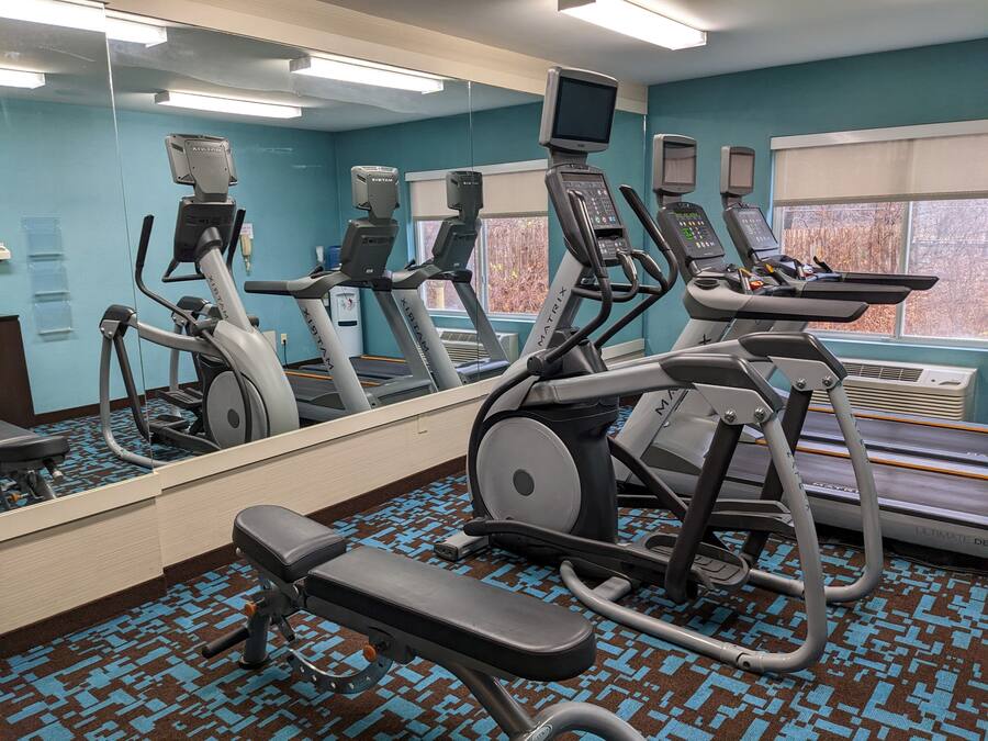 A gym with treadmills, an elliptical, and a bench.