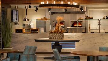 A modern kitchen with a central island, built-in oven, and a hanging light fixture.