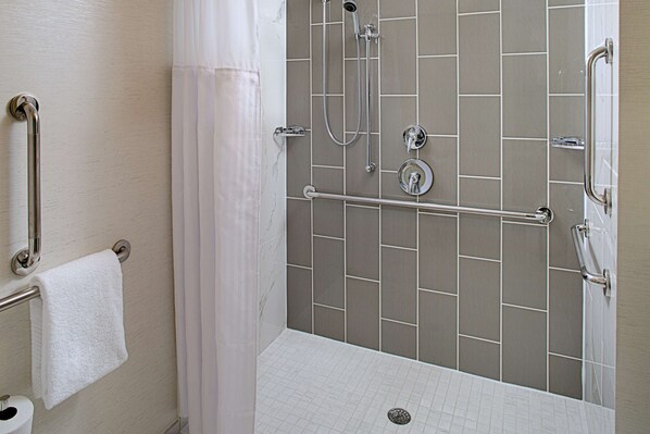 A shower area with a grab bar, a towel rack, and a showerhead.