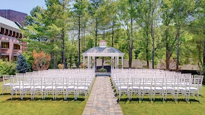 A gazebo with a tiled pathway leading to white chairs arranged in rows. - Hilton Boston/Dedham (Dedham)