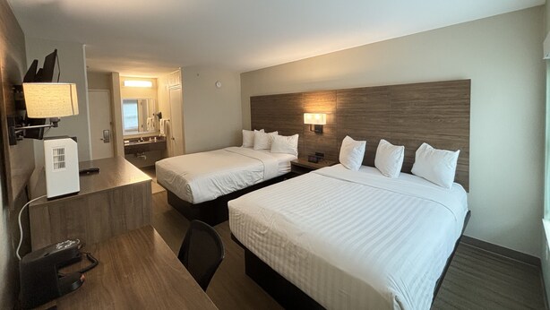 A hotel room with two beds, a desk, a chair, a mirror, and a lamp. - Baymont by Wyndham Lake Park Valdosta I-75 (Lake Park)