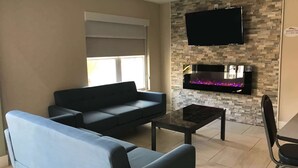 A living room with a sofa, a coffee table, and a flat-screen TV mounted on a stone wall. - Baymont by Wyndham Lake Park Valdosta I-75 (Lake Park)
