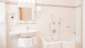 A bathroom with a sink, mirror, and shower.