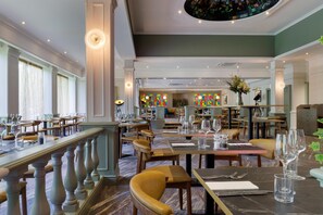 A restaurant with multiple dining tables and chairs, a staircase, and a view of the dining area.
