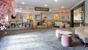 A hotel lobby with a bar area, seating arrangements, and a sign reading 'CASK & SOUNDT'.