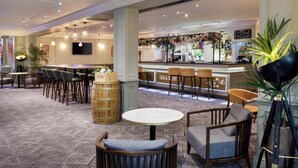 A hotel lobby with a bar area, seating arrangements, and a decorative plant.