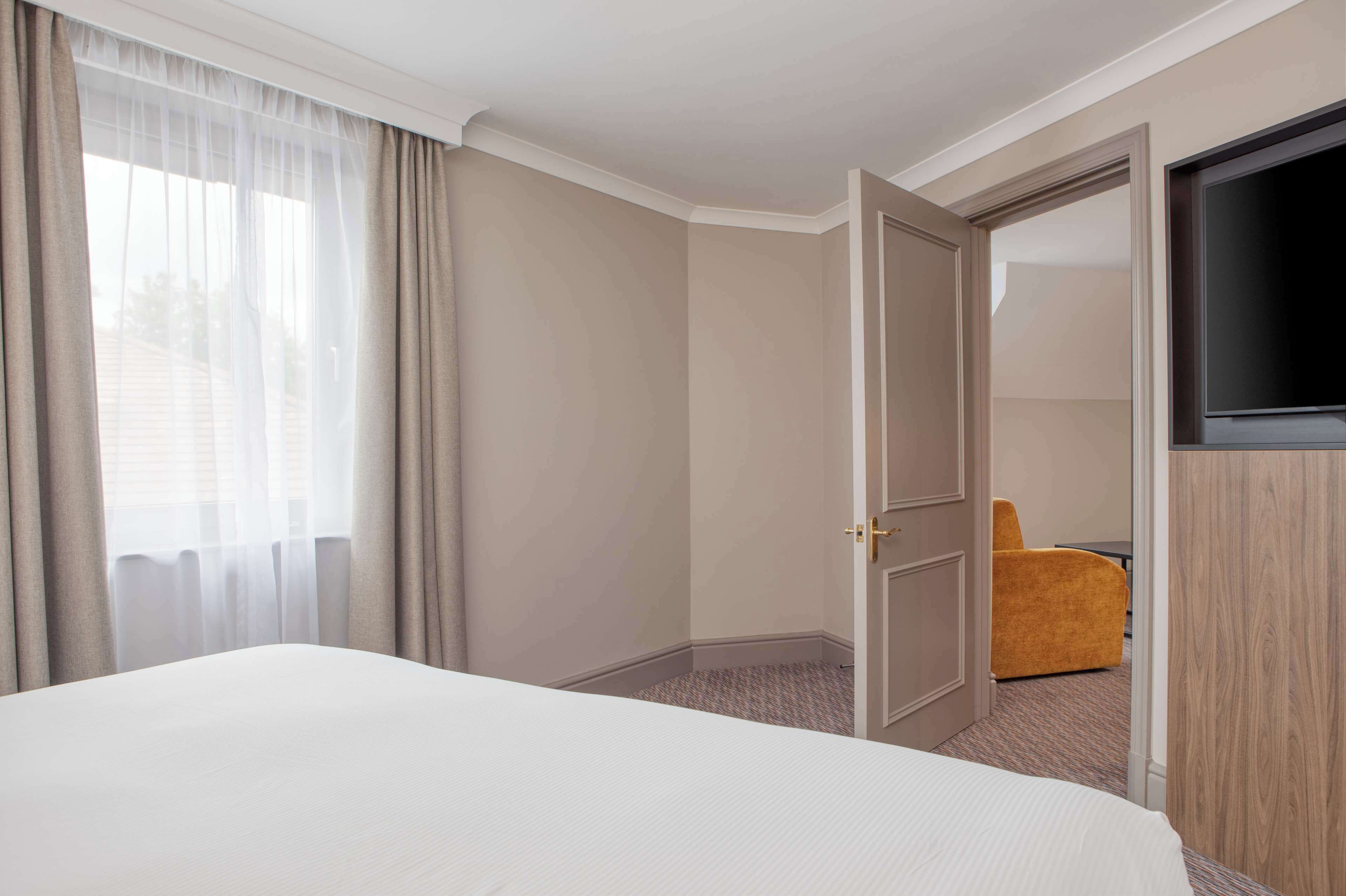 Une chambre d’hôtel avec un grand lit, une télévision et une porte donnant sur un coin salon.