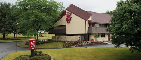 Un Red Roof Inn de dos pisos, con fachada de piedra y un jardín delantero cuidado.