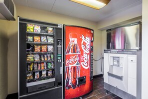 A vending machine with a Coca-Cola logo and a separate snack vending machine with various snacks.