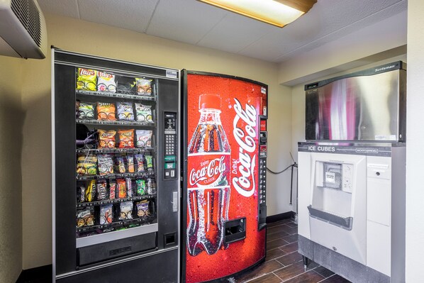 A vending machine with a Coca-Cola logo and a separate snack vending machine with various snacks.