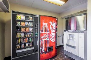 Una máquina expendedora con el logotipo de Coca-Cola y otra máquina de aperitivos con diferentes opciones.