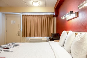 Ein Hotelzimmer mit Bett, Heizung, Fernseher und Wandleuchte.