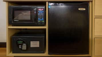 Una cocina equipada con microondas, refrigerador y una caja fuerte con cerradura digital.