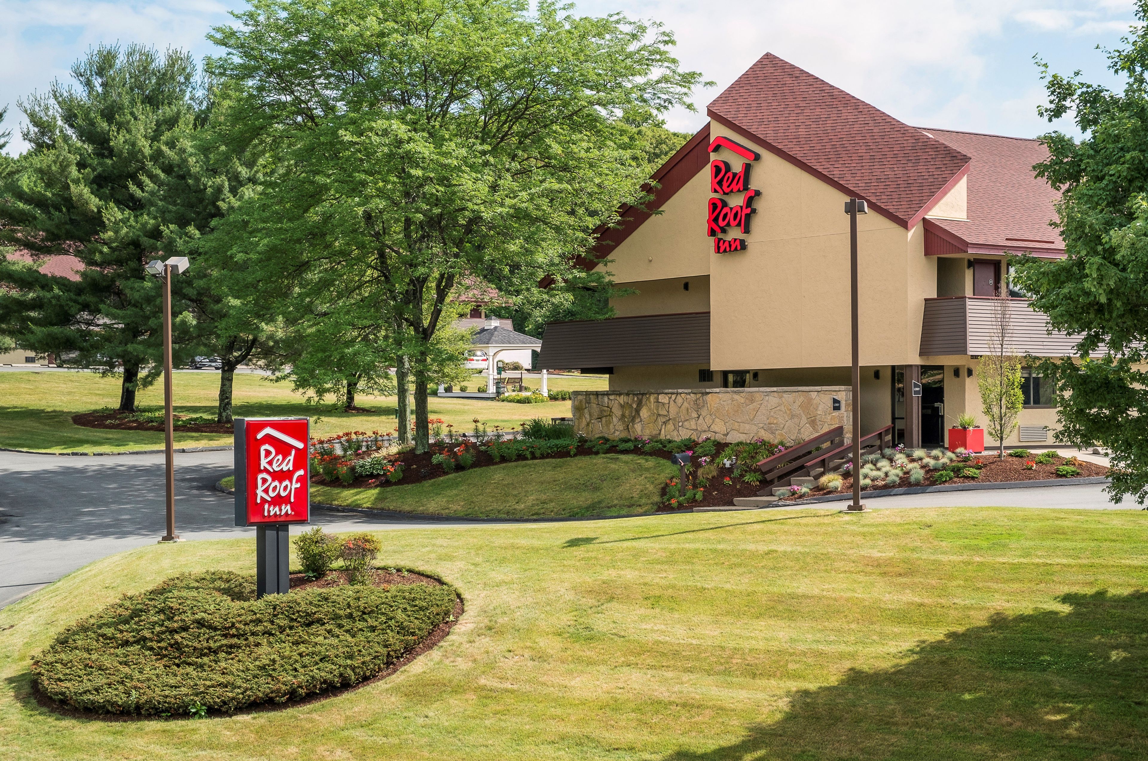 A Red Roof Inn with a two-story structure, a stone facade, and a red roof.