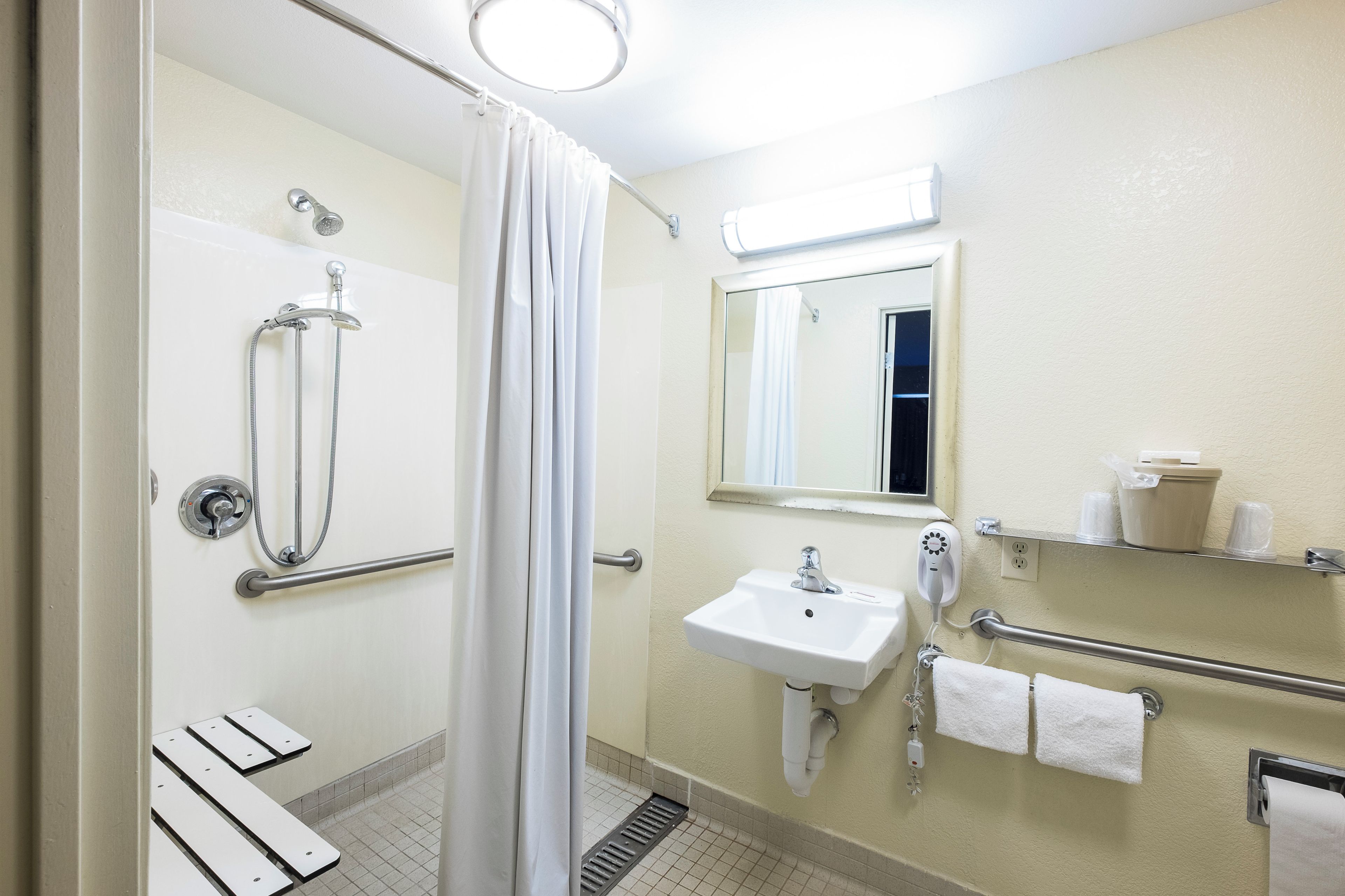 A bathroom with a shower, a sink, a mirror, and a toilet.