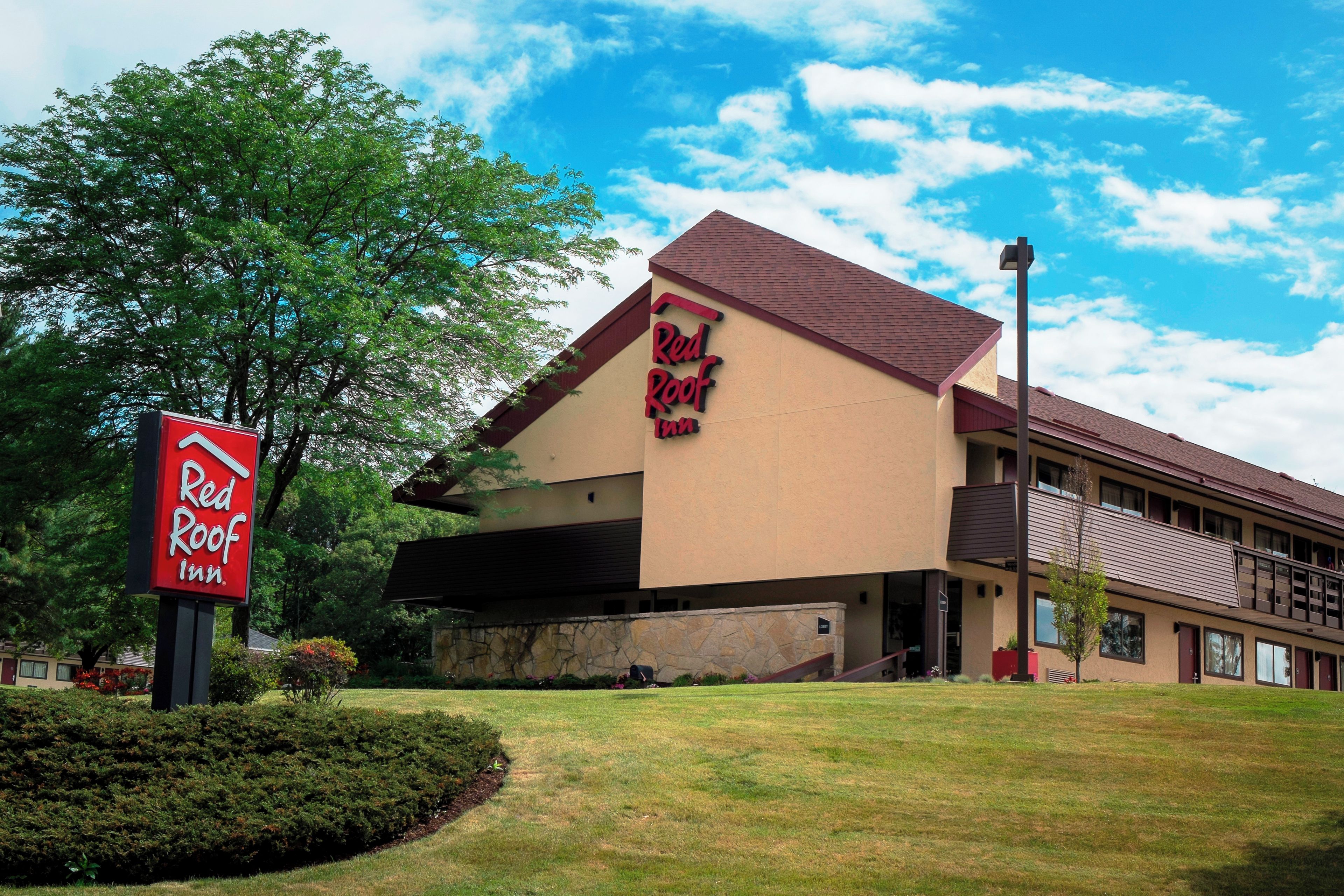 Un hotel Red Roof Inn con un edificio de dos pisos, fachada de piedra y estacionamiento.