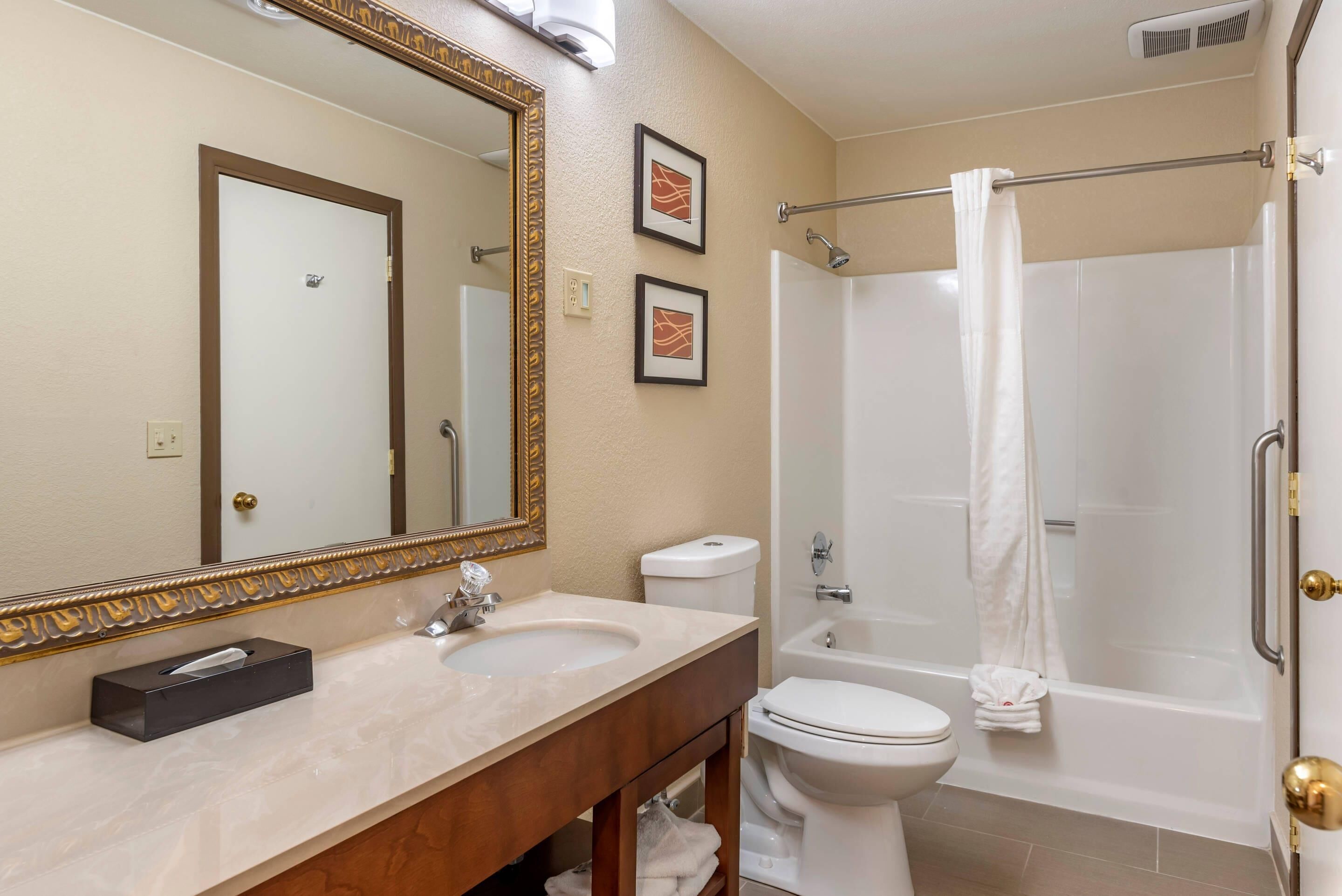 Un baño con un espejo grande, un lavabo, un inodoro y una bañera.