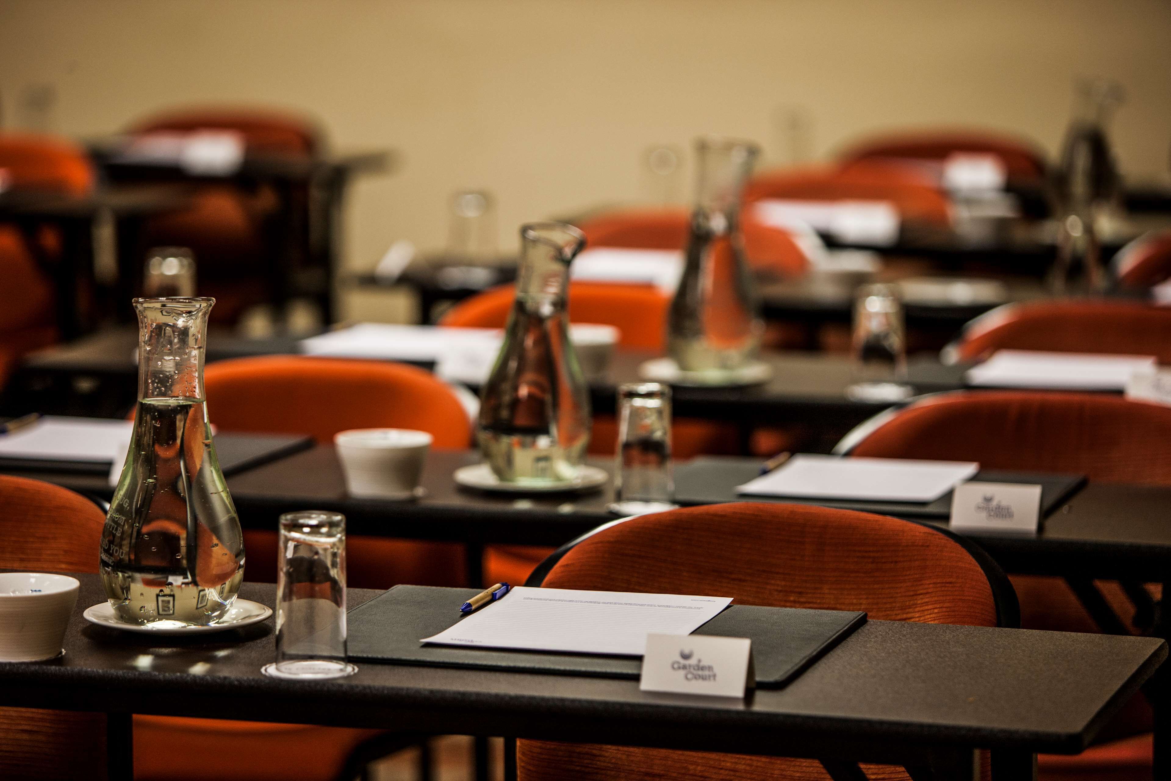 A conference room with tables set up for a meeting, each with nameplates, water bottles, and glasses.