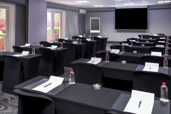 A conference room with multiple tables, each equipped with nameplates, water bottles, and pens. - Garden Court East London (East London)