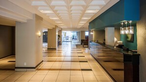 Un vestíbulo de hotel con mostrador de recepción, zona de estar y vistas del propio vestíbulo al fondo.