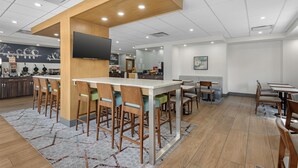 Un restaurante moderno con zona de bar, sillas de madera y alfombra estampada.