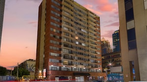 Un hotel de varios pisos con diseño moderno, ubicado en una esquina destacada y con vistas panorámicas al paisaje urbano.
