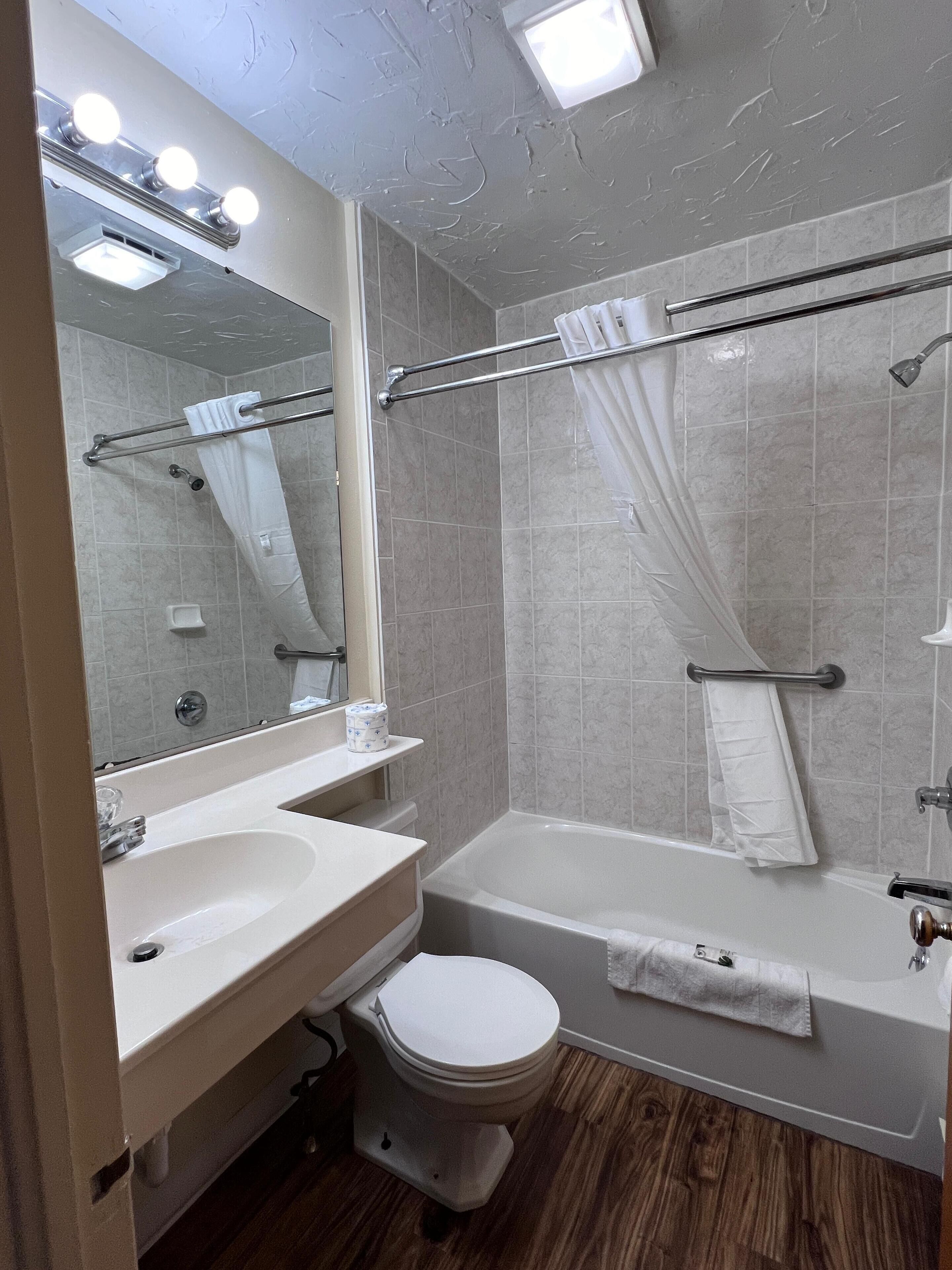 A modern bathroom with a vanity, sink, toilet, and bathtub.