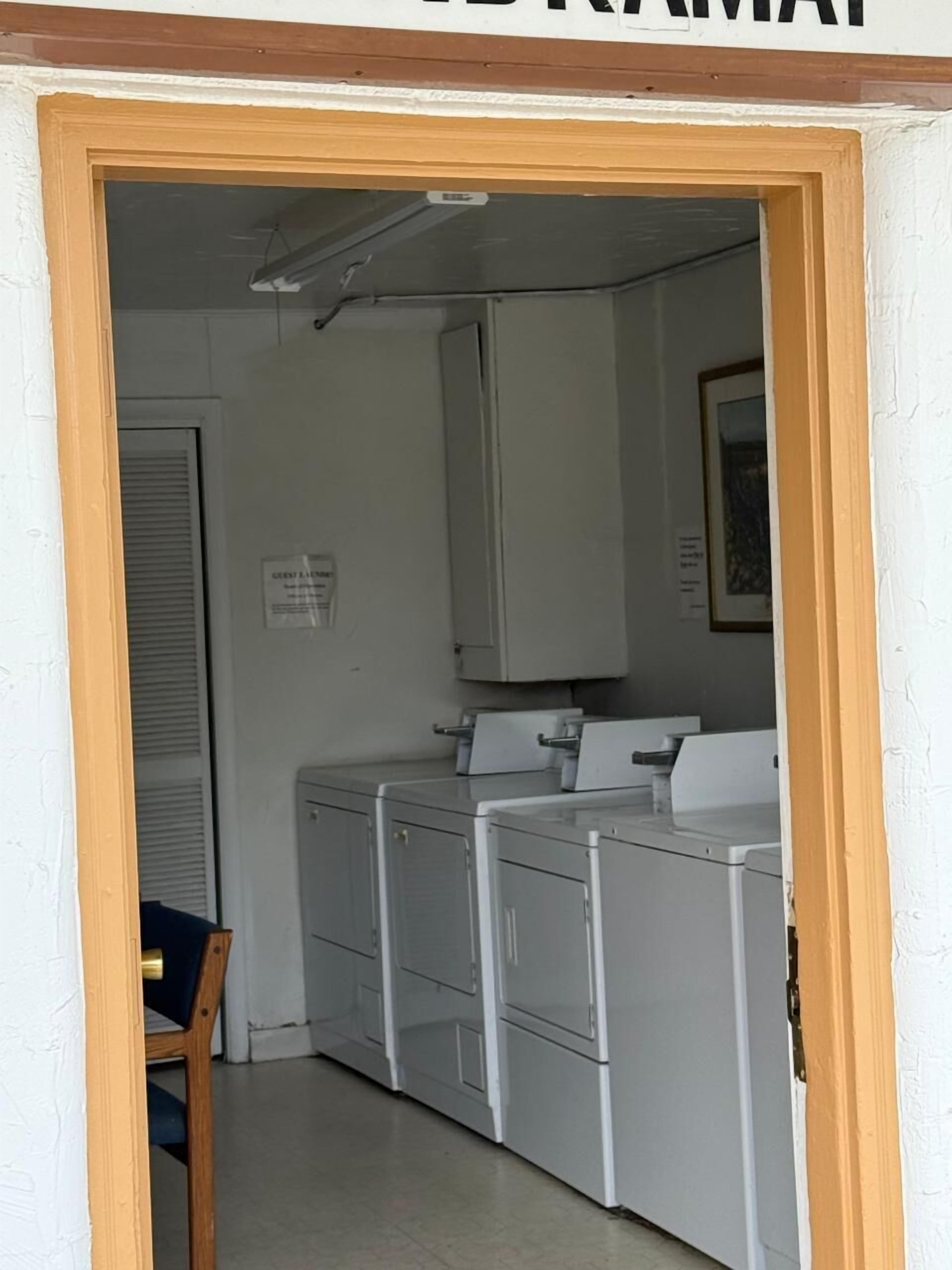 Un cuarto de lavandería con cuatro lavadoras y un tendedero.