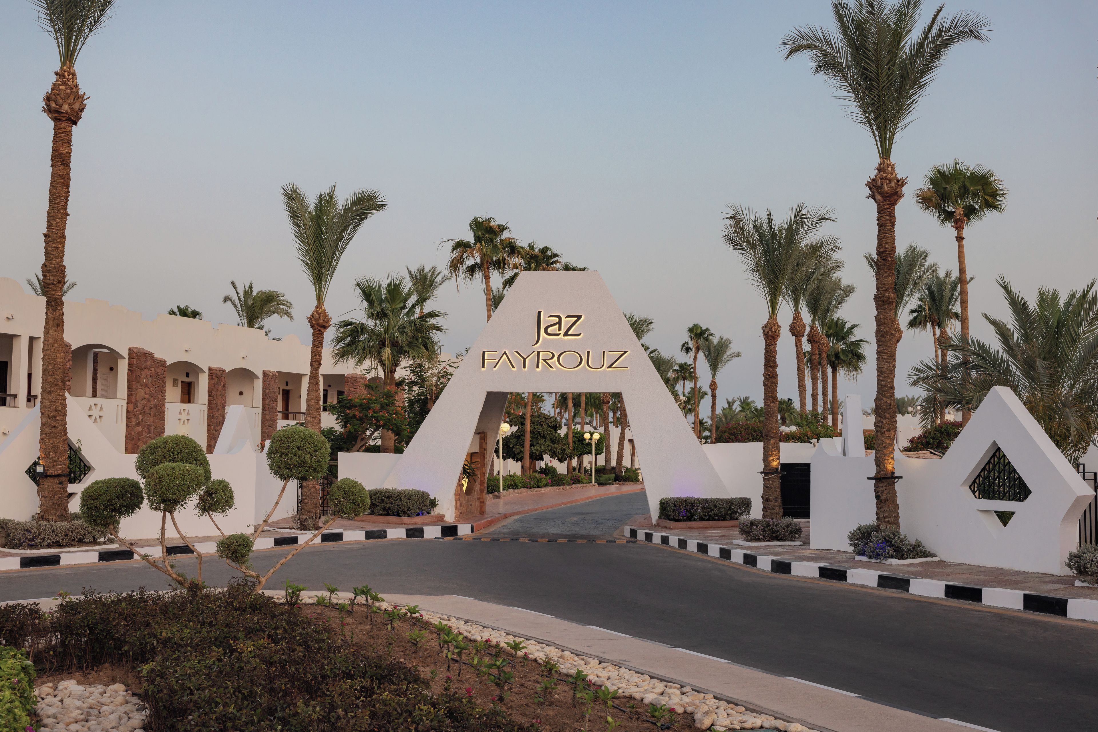 A hotel entrance with a prominent sign, palm trees, and a modern building facade.