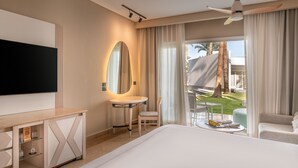 A hotel room with a bed, a TV, a desk with a mirror, a small table, a chair, and a view of the outdoors. - JAZ Fayrouz (Sharm El Sheikh)