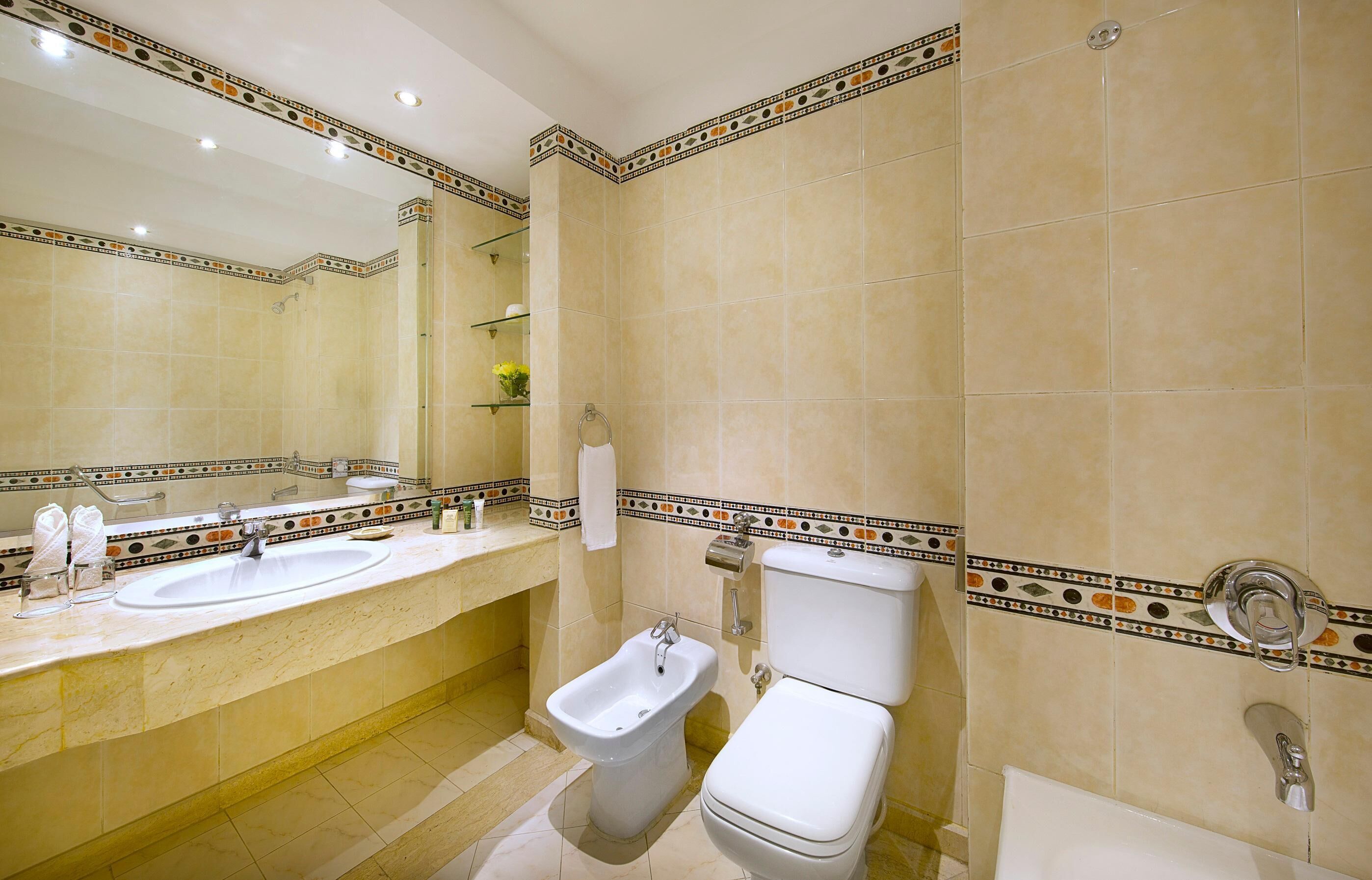 Un bagno con lavandino, bidet, WC e uno specchio.