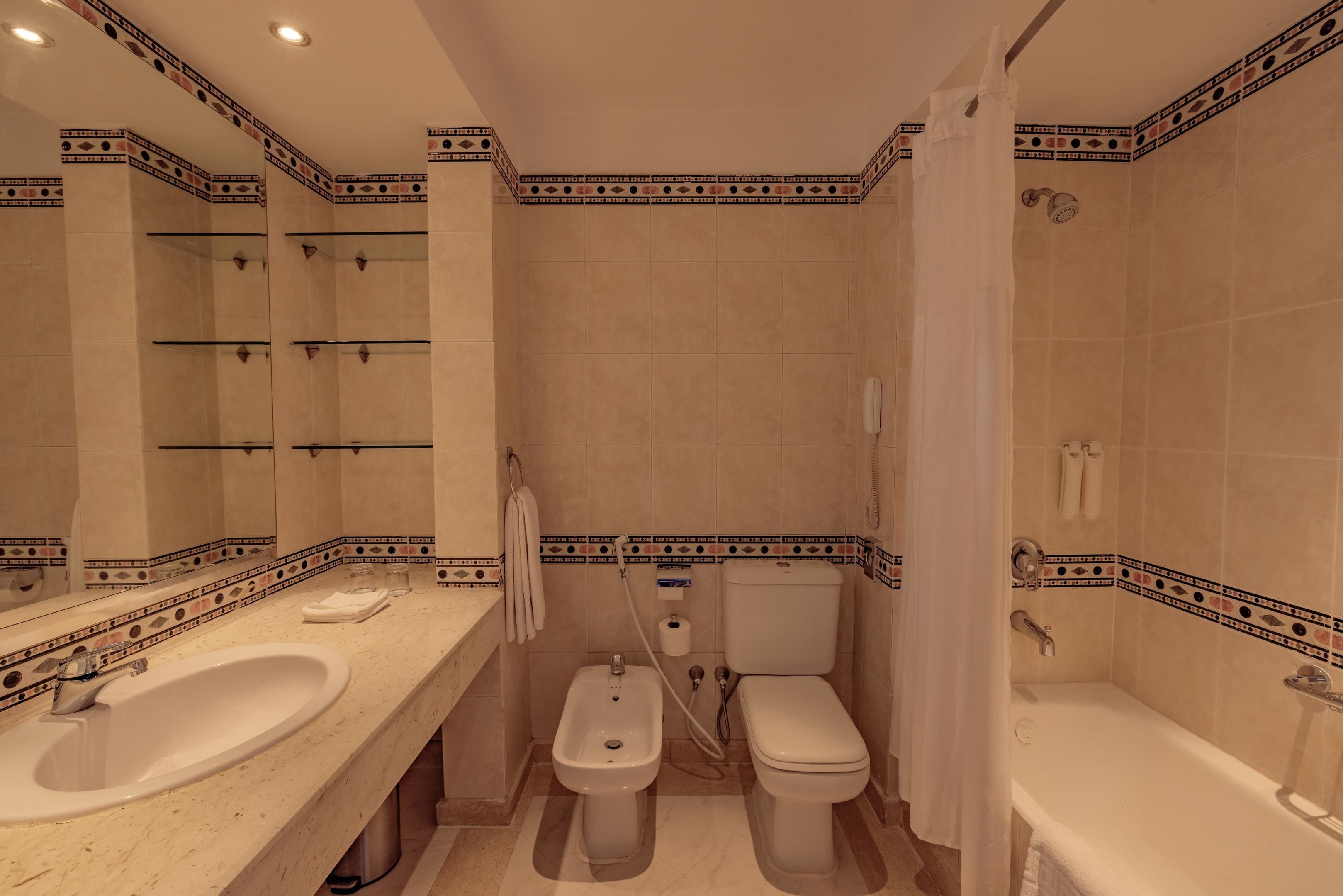A bathroom with a sink, bidet, toilet, and bathtub.